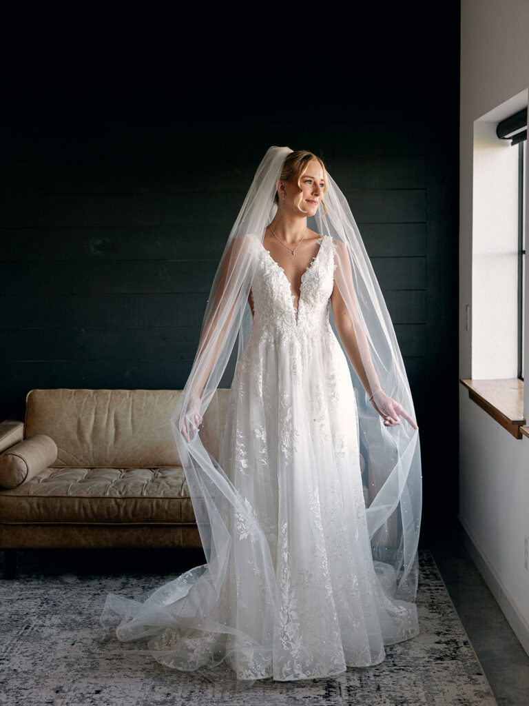 Bride standing near window light in groom suite