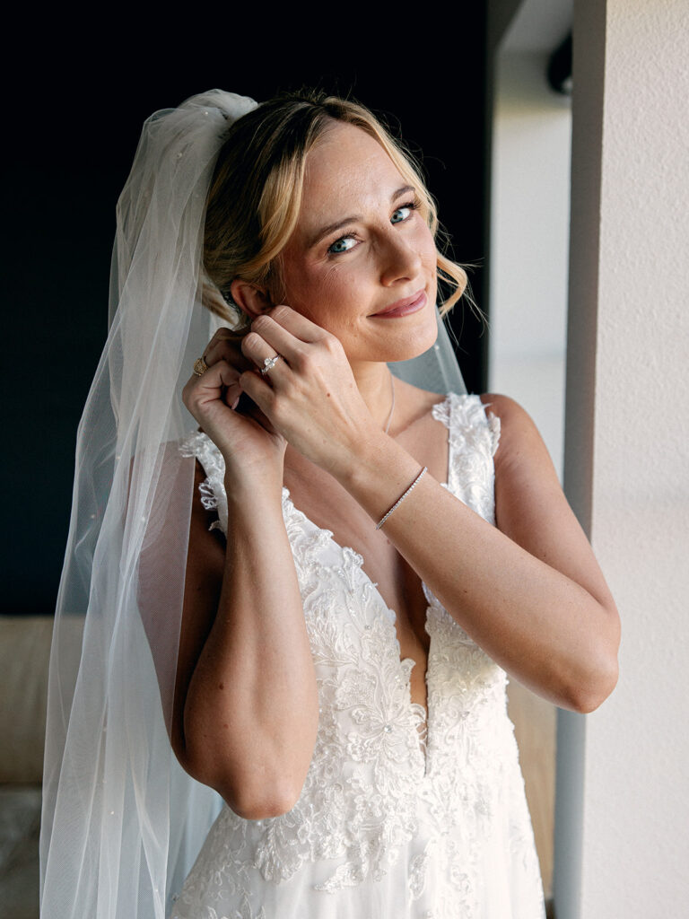 Bride standing in groom suite fixing earring