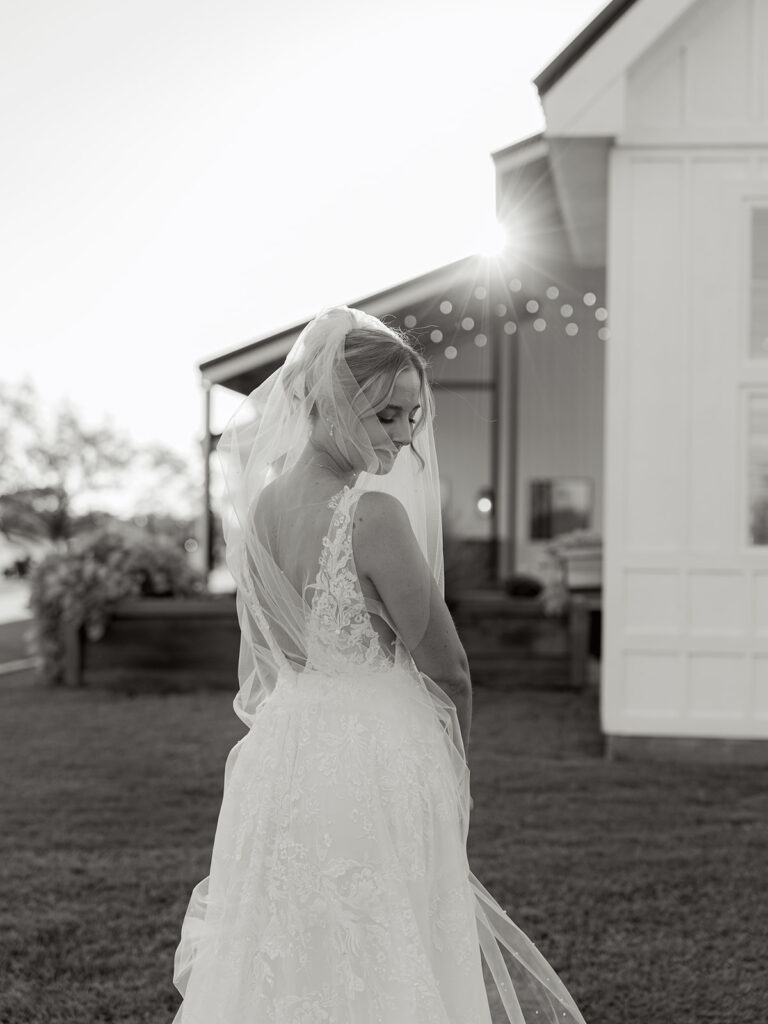 black and white sun flare photo with bride looking down over her shoulder 