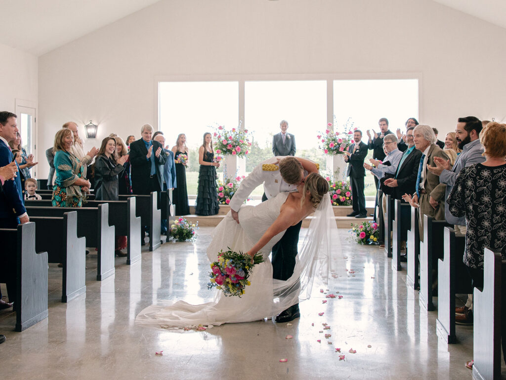 bride and groom kissing in a dip a they recess back down the ceremony aisle for their wedding at Davis & Grey Farms