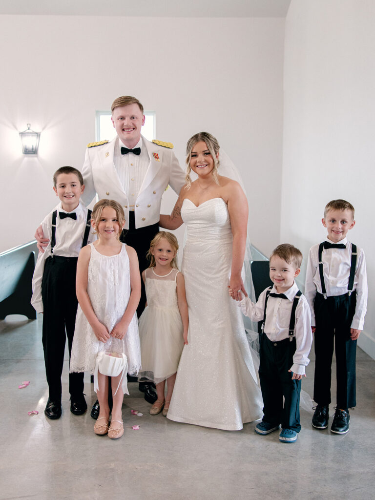 bride and groom with their 2 flower girls and 3 ring bearers posing for a photo