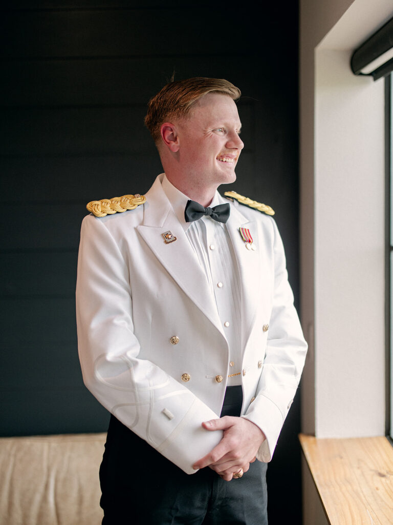 groom waiting to see his bride looking out the window in his army wedding attire
