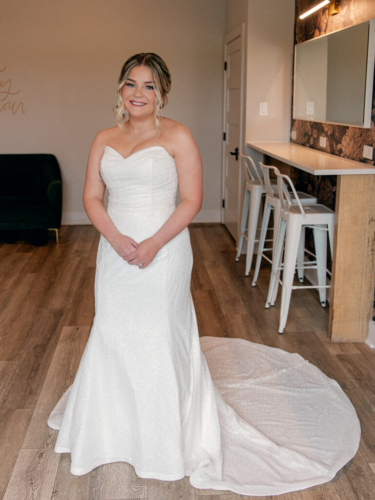 bride in bridal suite in wedding dress smiling at the camera