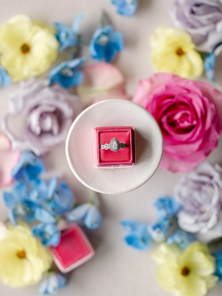 her ring styled on a flat lay surrounded by bright wedding flowers