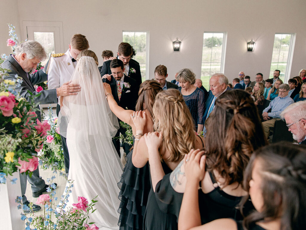 family praying over couple at altar