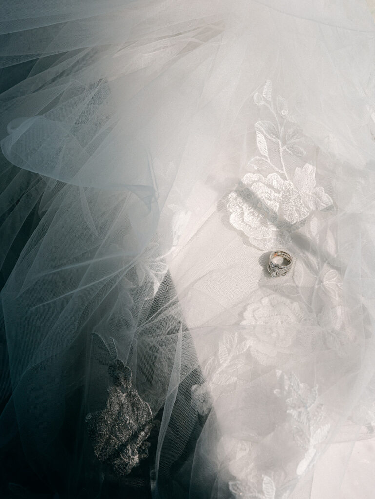 Bride's ring and veil in the shadows of window light
