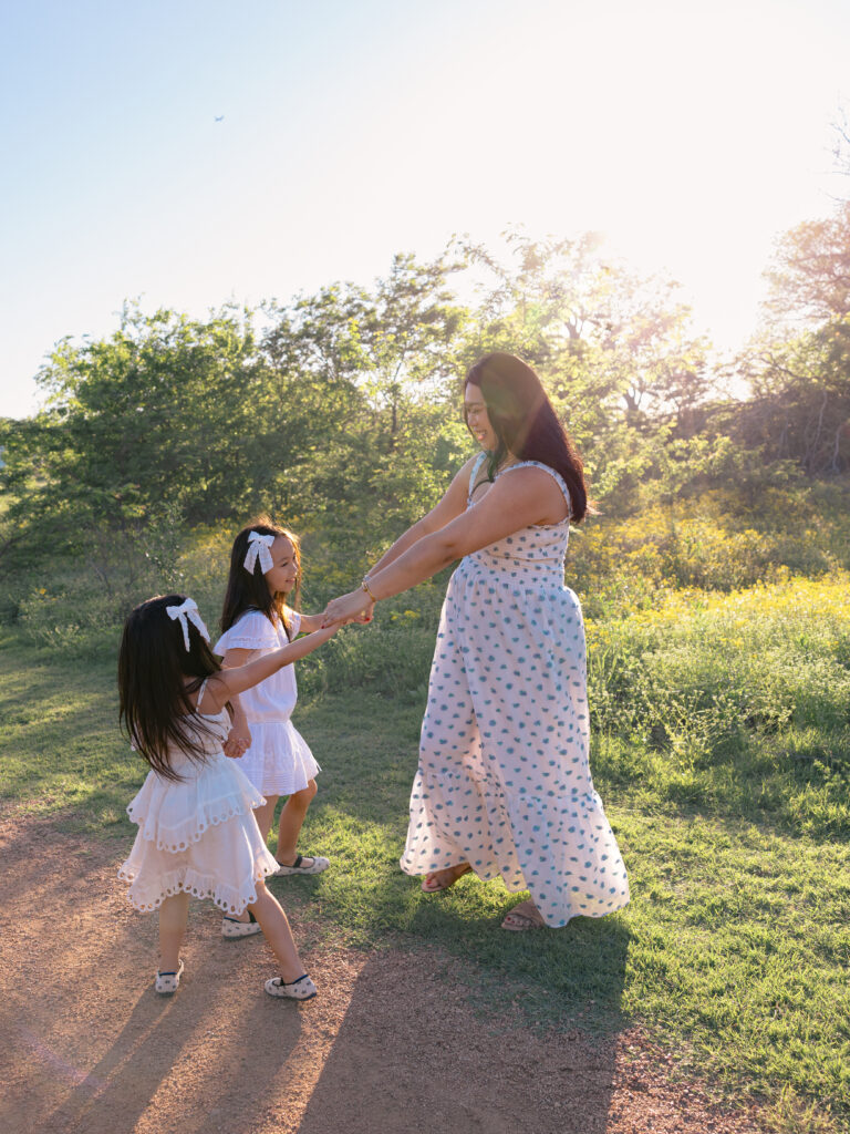 prepare kids for photoshoot by having mom and 2 young daughter's  play ring around the rosy during a family photoshoot
