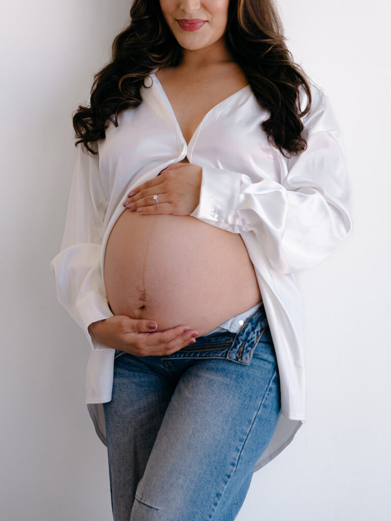 studio maternity session with pregnant belly the feature with a open white button down and undone jeans