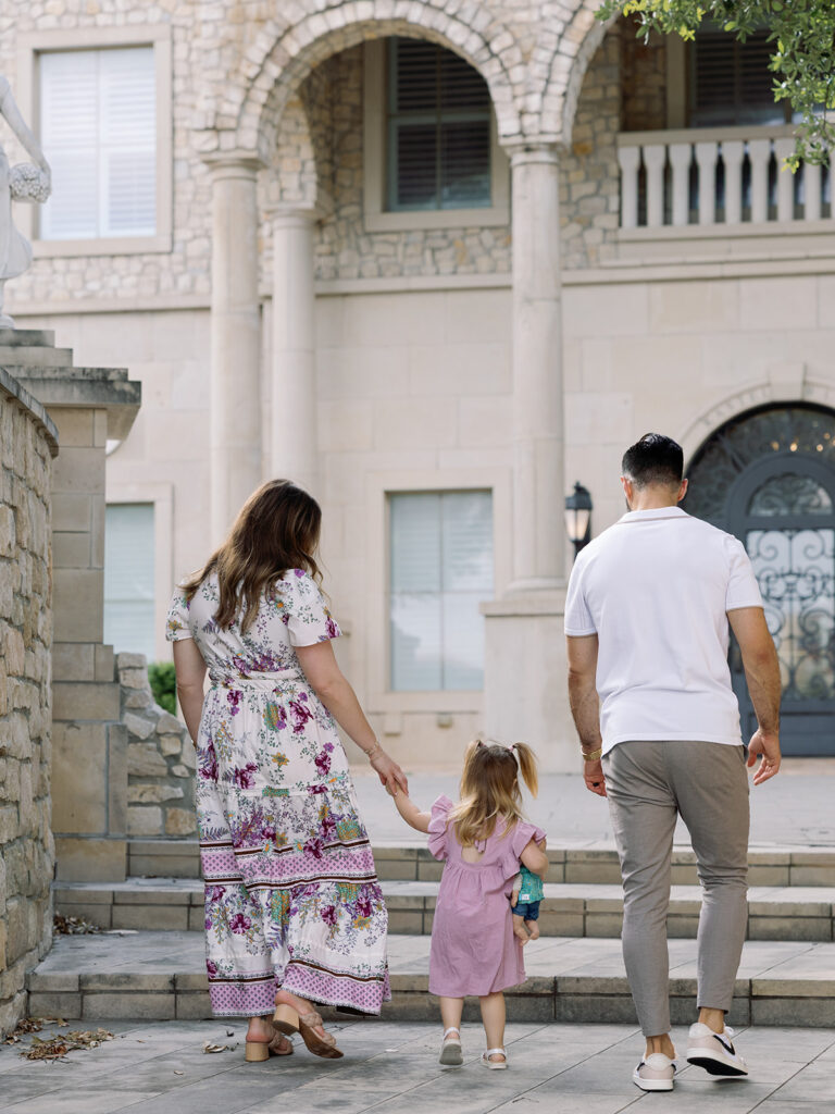 mom dad and young daughter walking away from camera during family photo session in north dallas