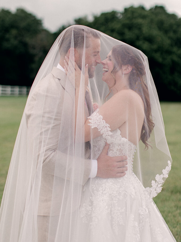 Bride and groom embracing beneath her veil